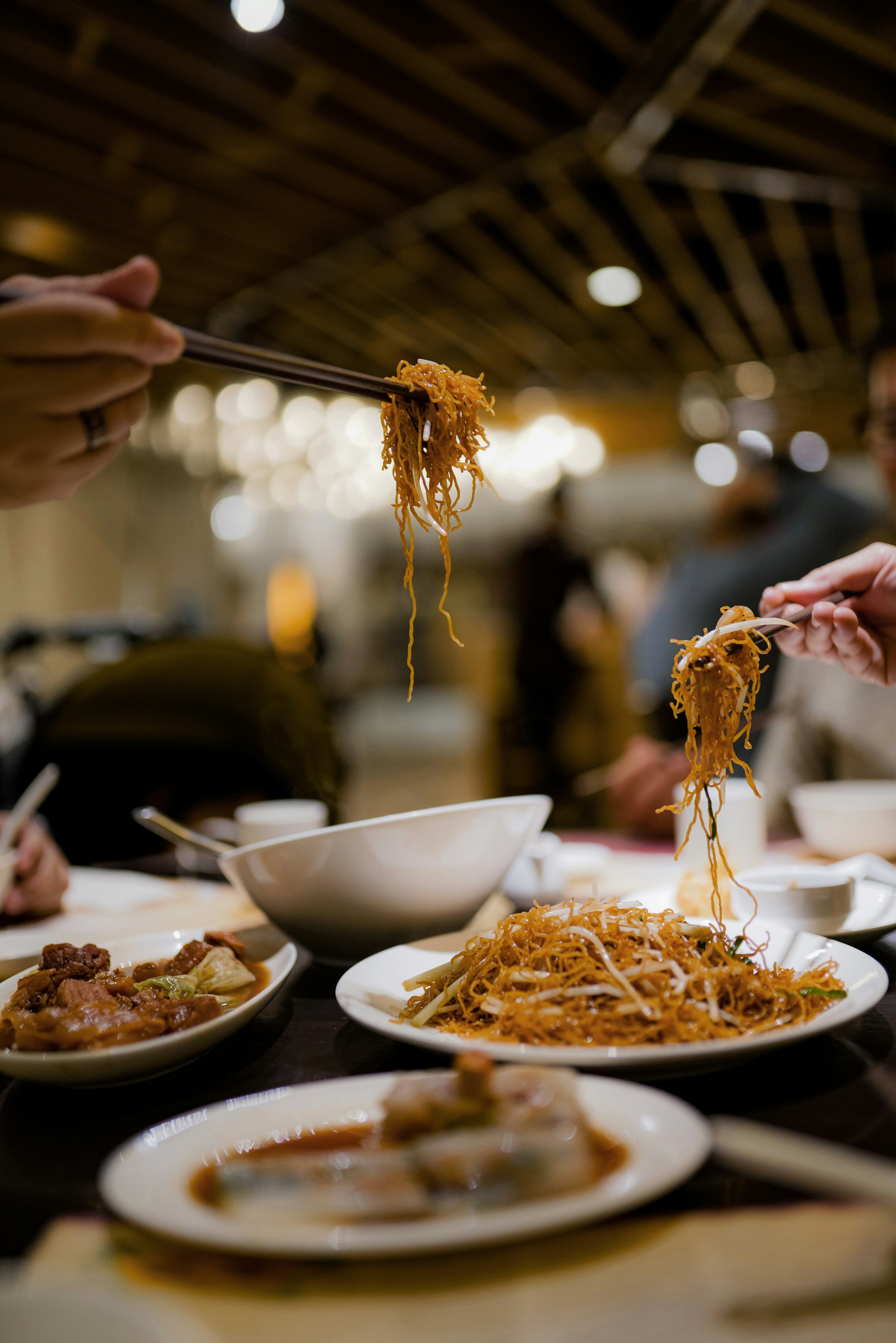 Guests sharing crispy noodles with chopsticks at a cozy local restaurant